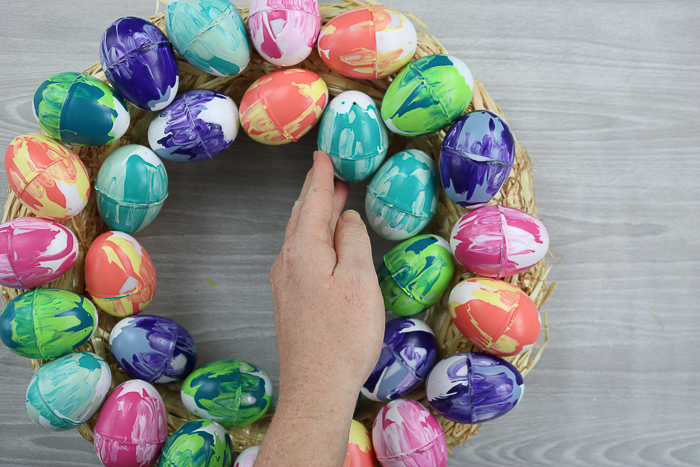 Covering a wreath form in Easter eggs.