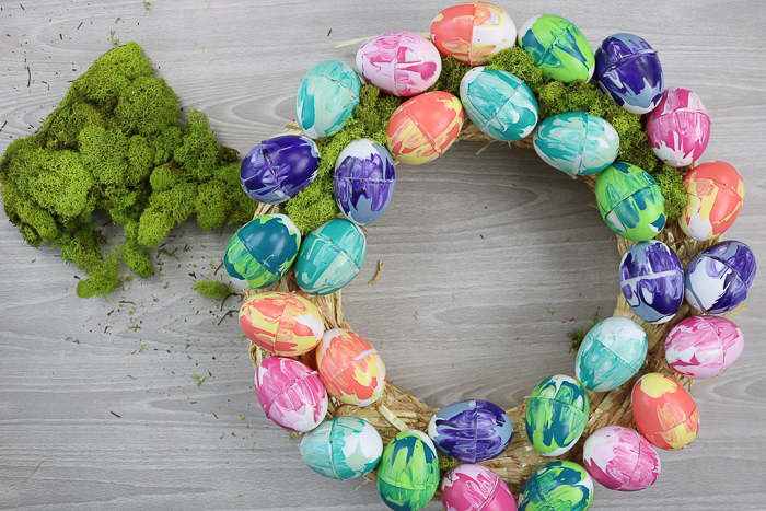 Adding moss to an Easter wreath with marbled eggs.