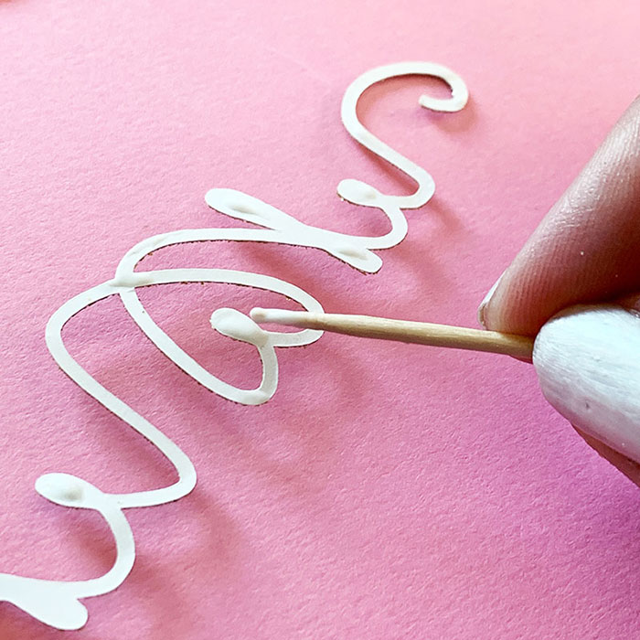 Adding glue to the back of the word mom cut from cardstock