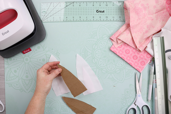 Adding cardboard to white fabric to complete bunny ears.