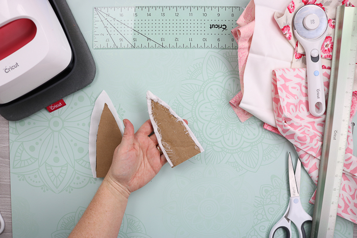 Using hot glue to secure fabric into place on cardboard bunny ears.