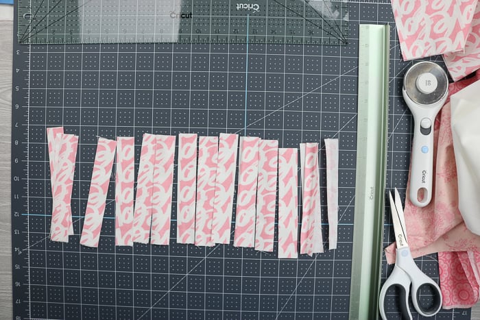 Using the Cricut rotary blade and cutting ruler to cut fabric into strips.