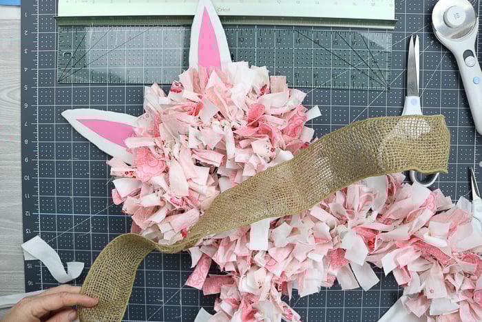 Using burlap ribbon to make a bow for a bunny rag wreath.