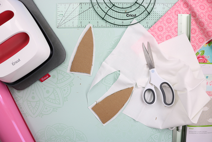 Covering cardboard bunny ears with white fabric to make an Easter rag wreath.