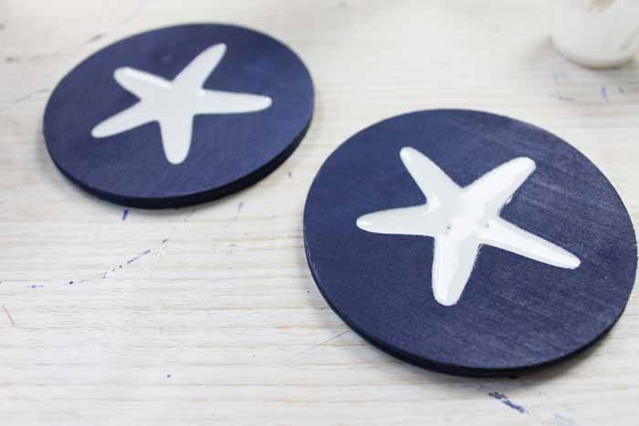 Paint your wood coasters, then fill the inlay star shape with white resin
