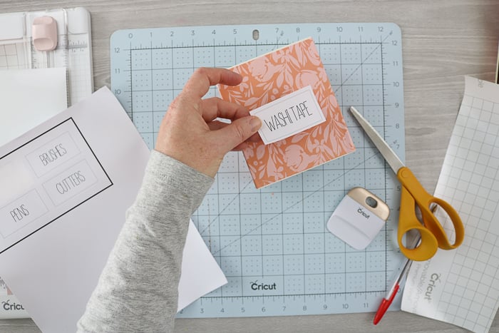 Adding printable organizer labels to the front of a wood box that has been covered in vinyl.