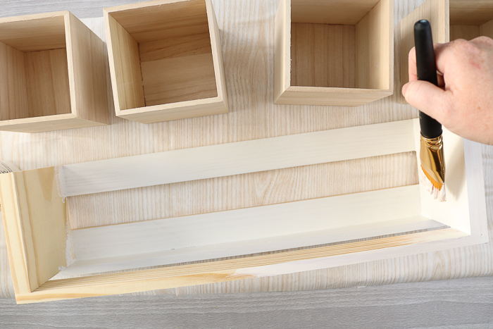 woman painting wooden shelf white