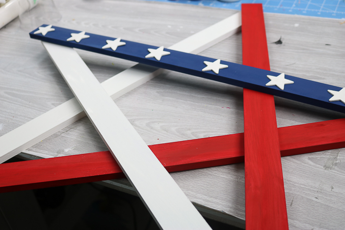 Lay out the painted wood slats into a star shape, then attach with adhesive