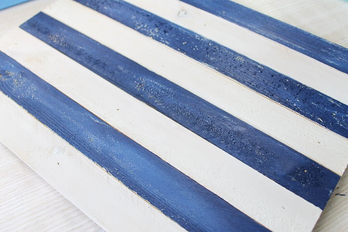 painting blue and white stripes on a pallet sign