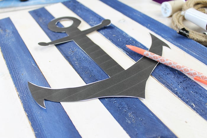 Tracing an anchor onto a rustic sign