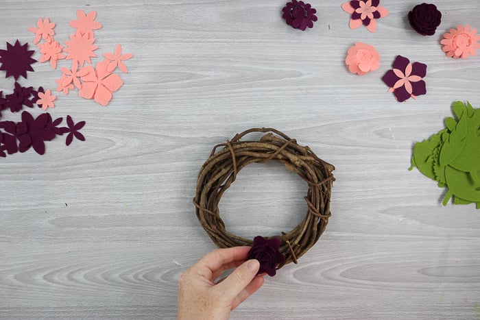 using hot glue to add flowers to a wreath form