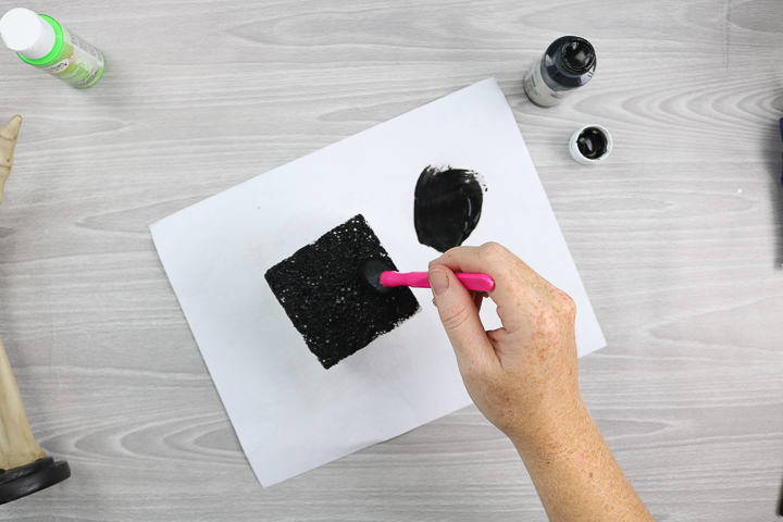 painting a foam block with a sponge brush