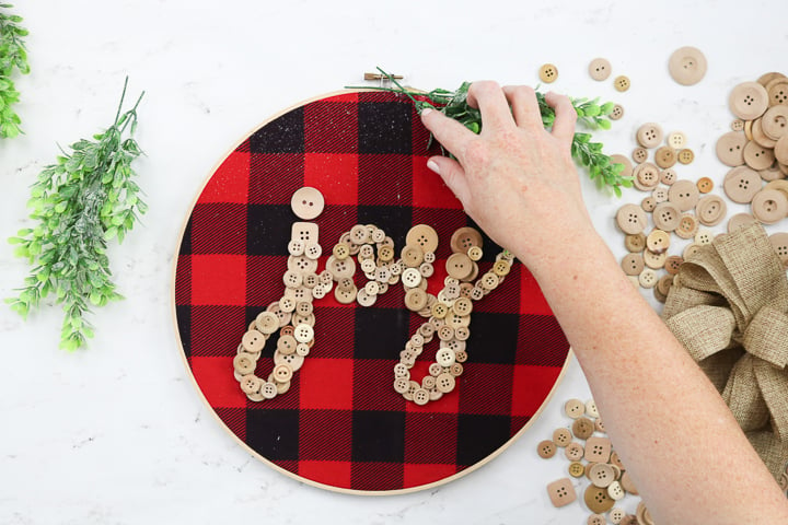 adding greenery to an embroidery hoop wreath