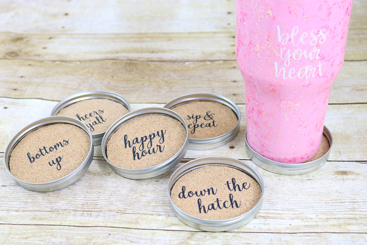 DIY mason jar lid coasters on a table with a hot pink decorative tumbler