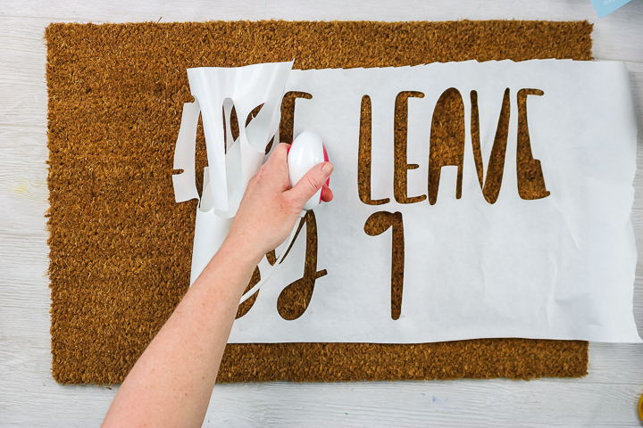 applying freezer paper stencil to a doormat