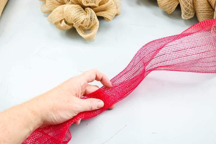adding red deco mesh to a wreath