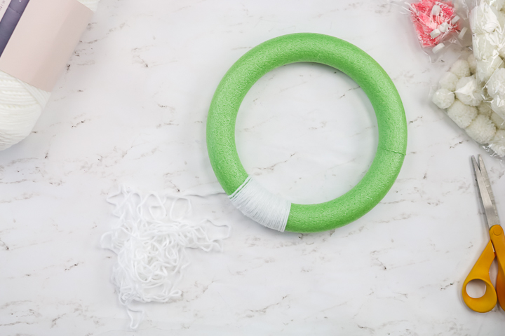 wrapping white yarn around a wreath form