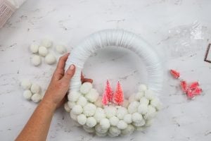 using hot glue to add pink bottle brush trees to a wreath