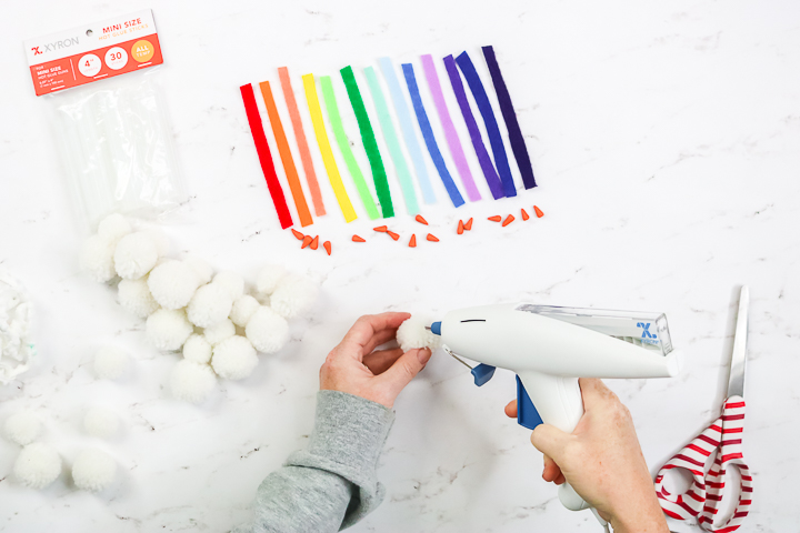 adding hot glue to white pom pom