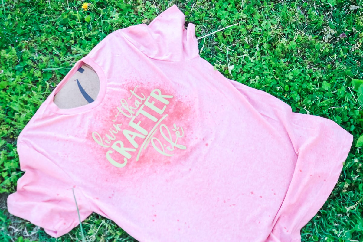 spraying bleach on vinyl on a shirt