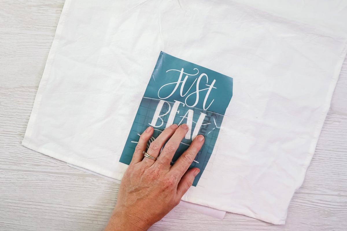 applying a vinyl stencil cut on a cricut to a tea towel