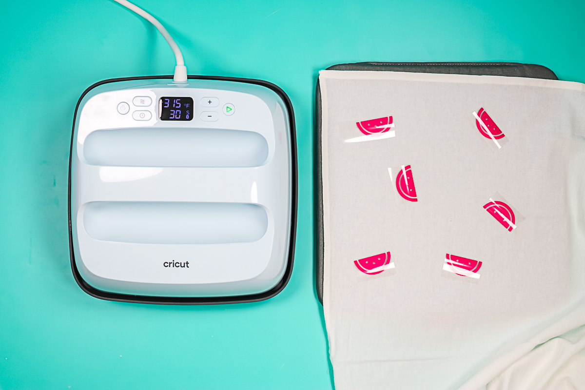 adding watermelon htv pieces to a tea towel