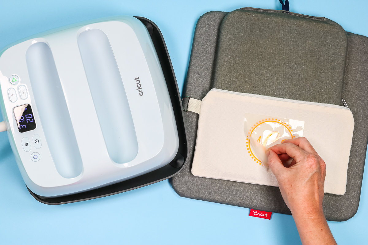 Removing carrier sheet from yellow HTV applied to a makeup bag.