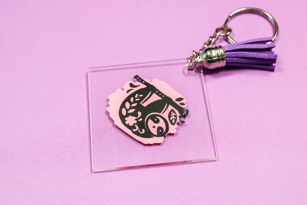 Sloth keychain with brush strokes on back.
