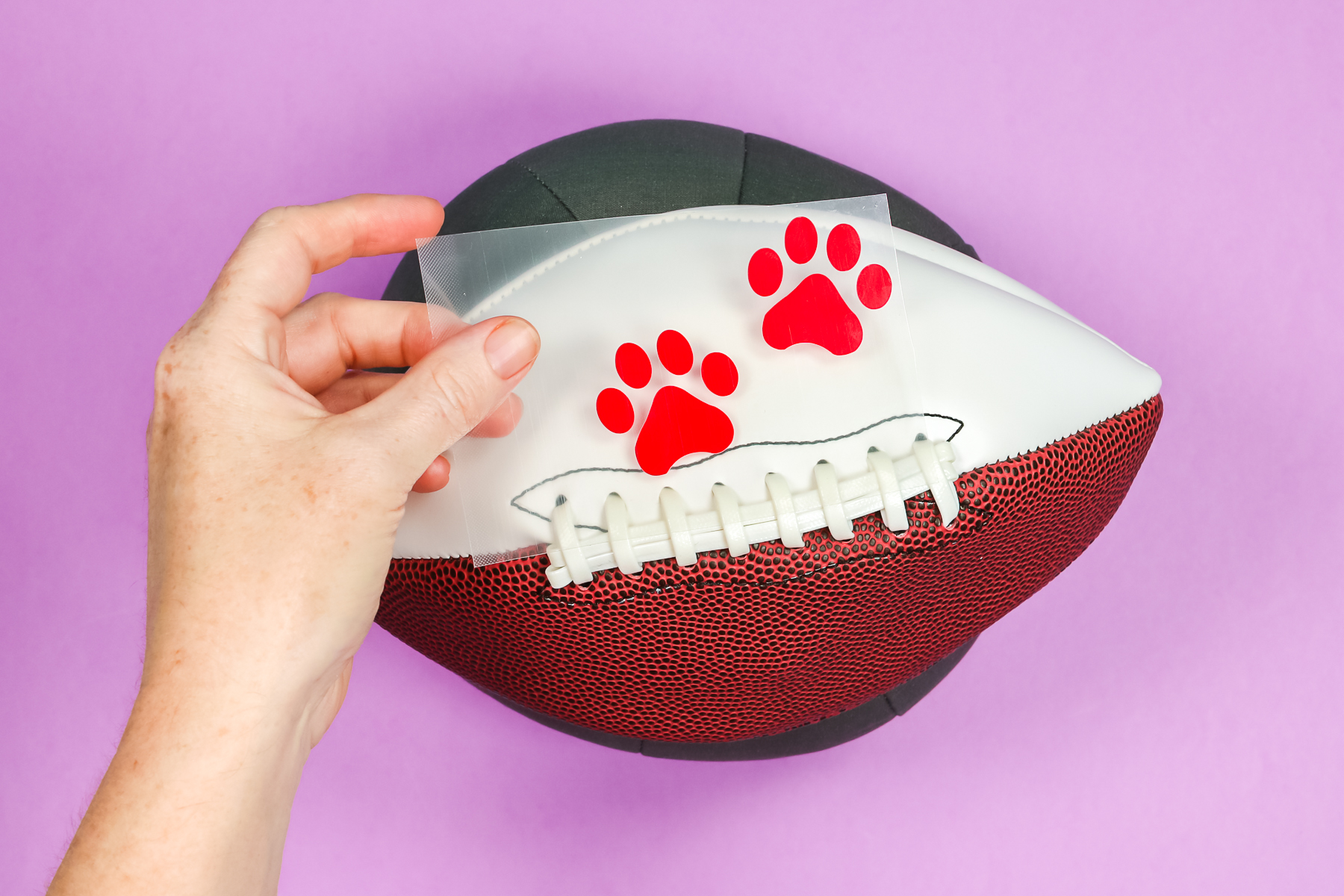 Cricut Hat Press form with deflated football and paw print HTV decals.
