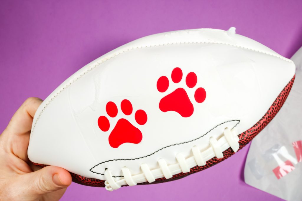 Deflated football with paw print HTV decals applied.