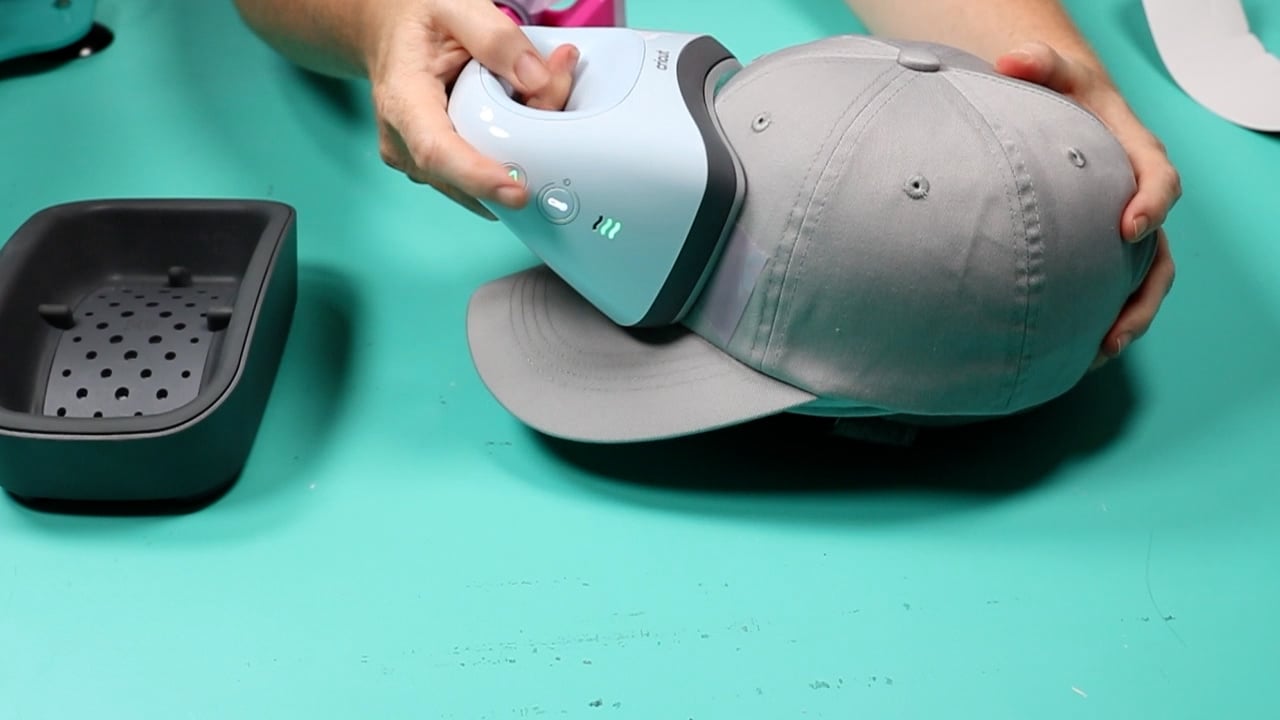 Cricut hat press applying HTV design to hat.