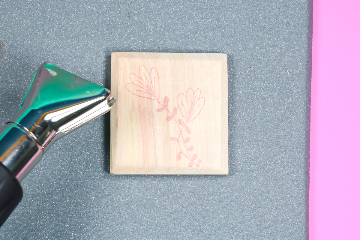 Heat gun applying heat to wood blank with scorch marker.