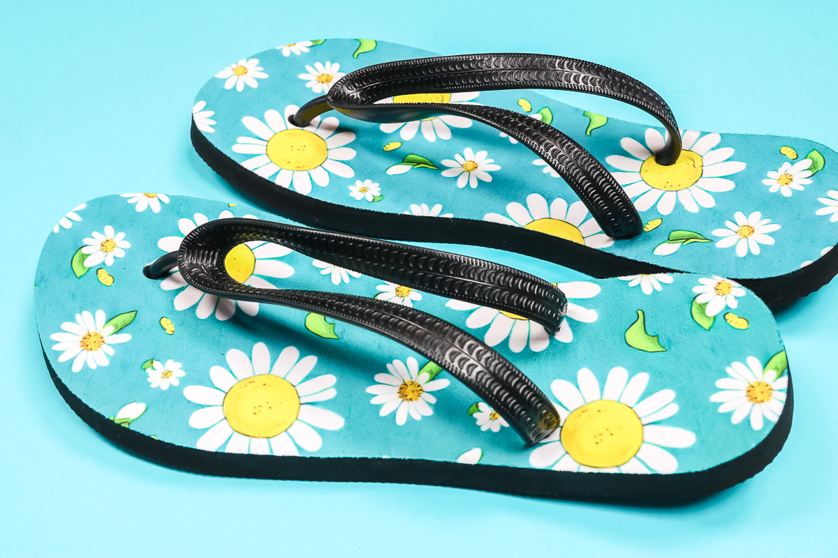 Close up of yellow daisy sublimation flip flops.