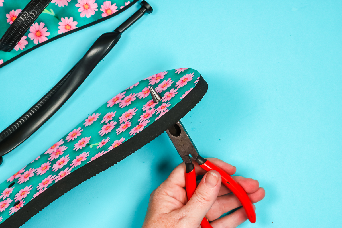 Needle-nose pliers through hole in flip flops.