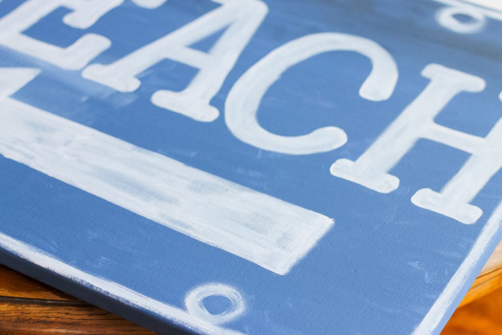 Ballard Designs Knock Off Beach Sign -- a great technique for getting a rusty appearance on a painted sign easily. You probably already have the secret ingredient in your kitchen! white paint on blue sign