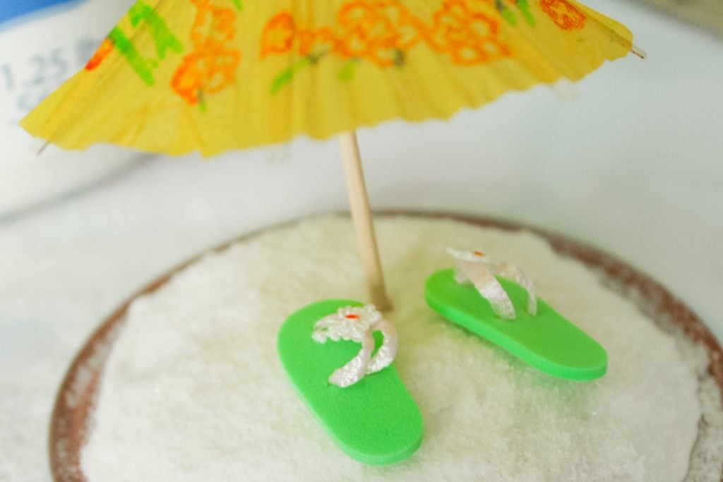 flip flops on sand with an umbrella