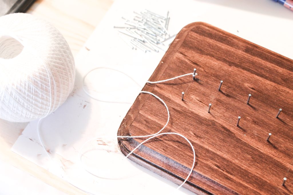 adding string to nails on a stained piece of wood