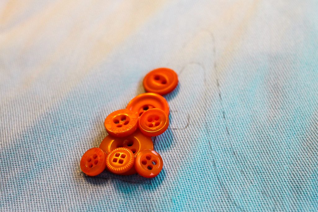 laying buttons on stenciled letter