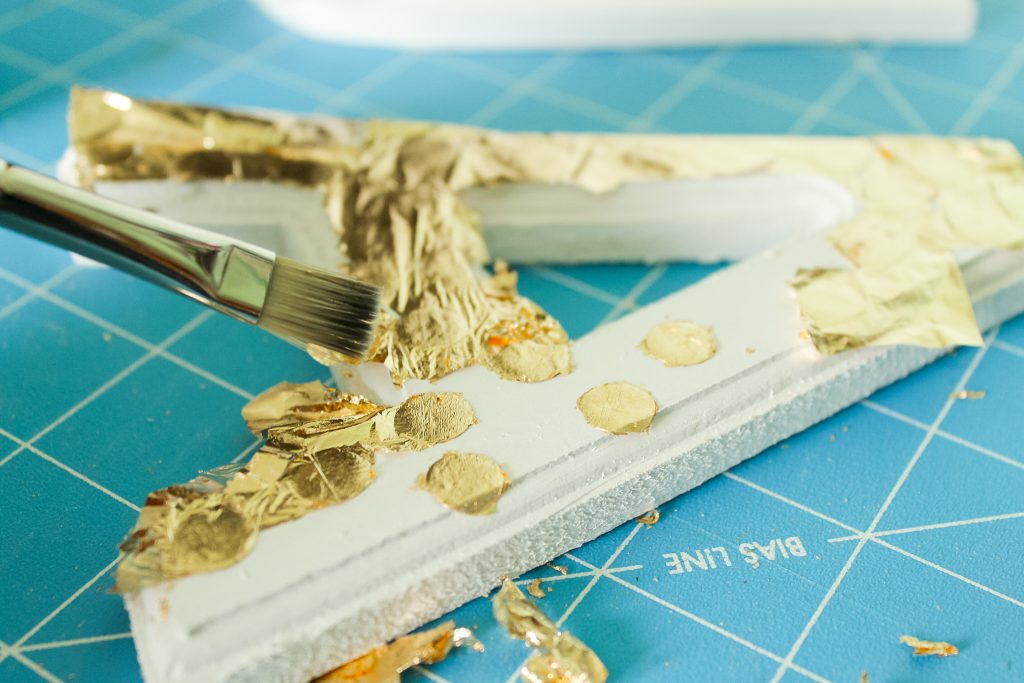 dry brushing gold leaf from a painted surface