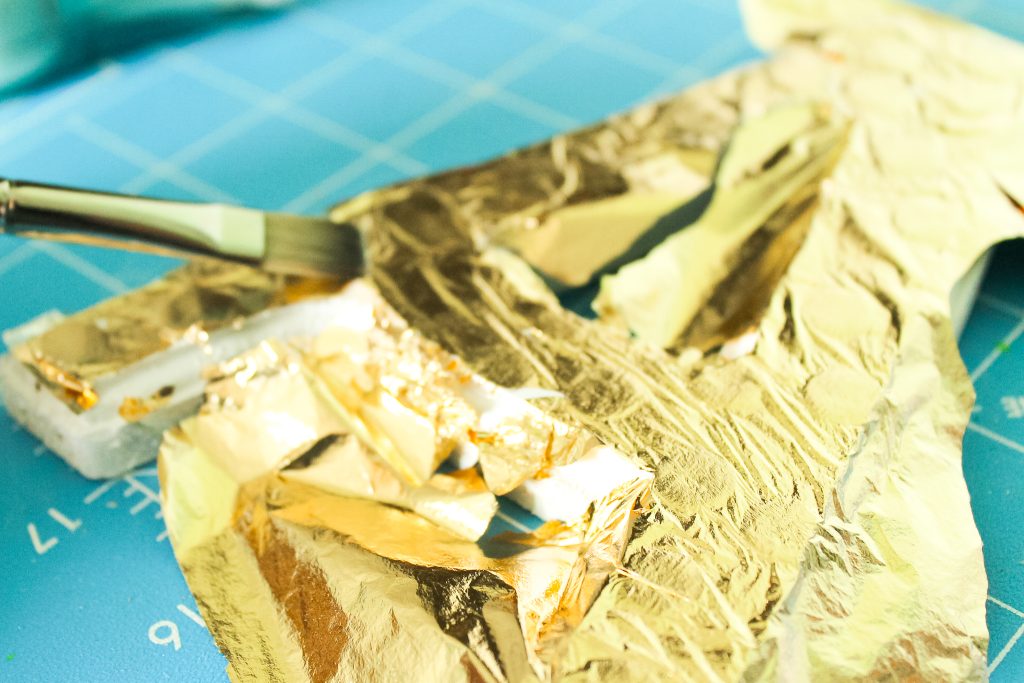 adding gold leaf to a painted letter
