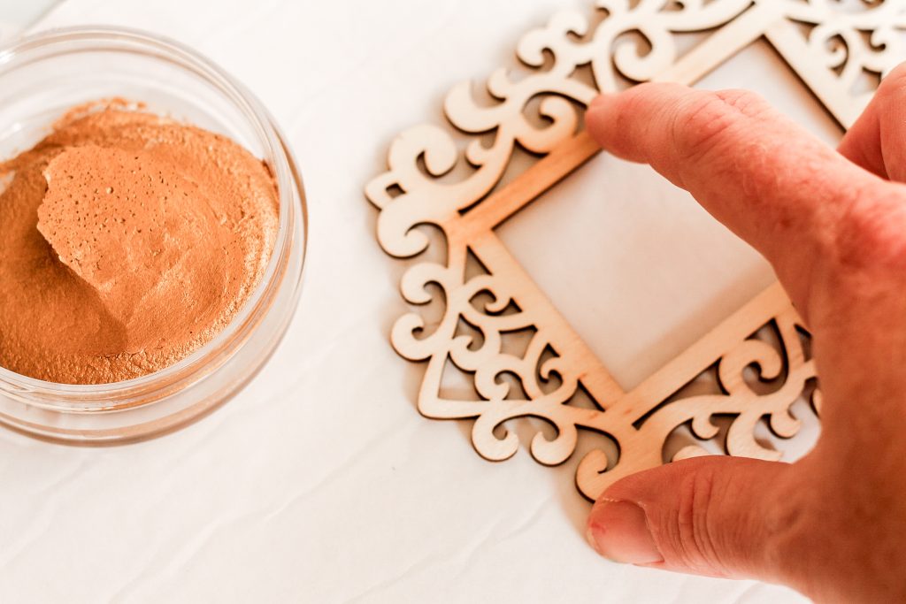 Using fingers to add gold luster to wooden frame