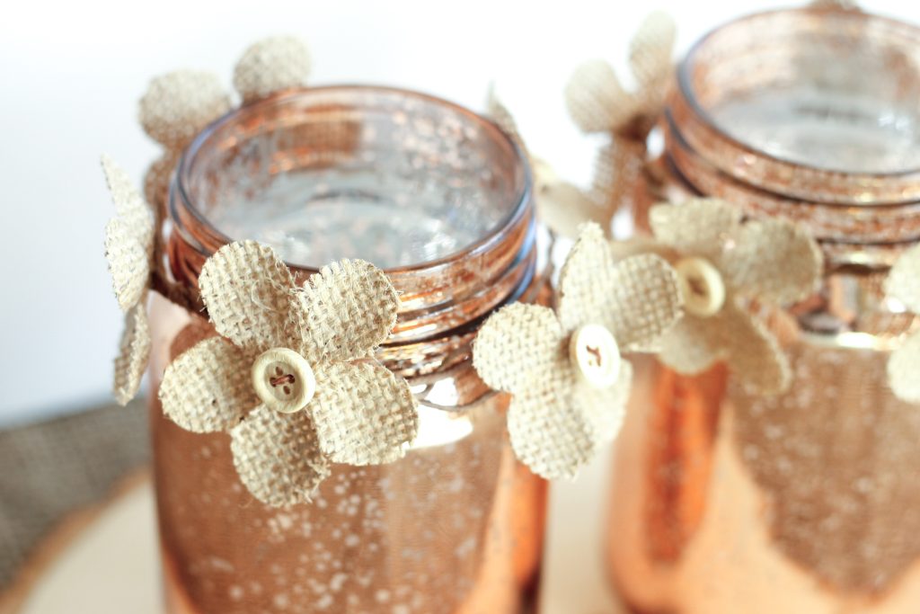 Close up image of ccopper Mason jars with burlap flowers
