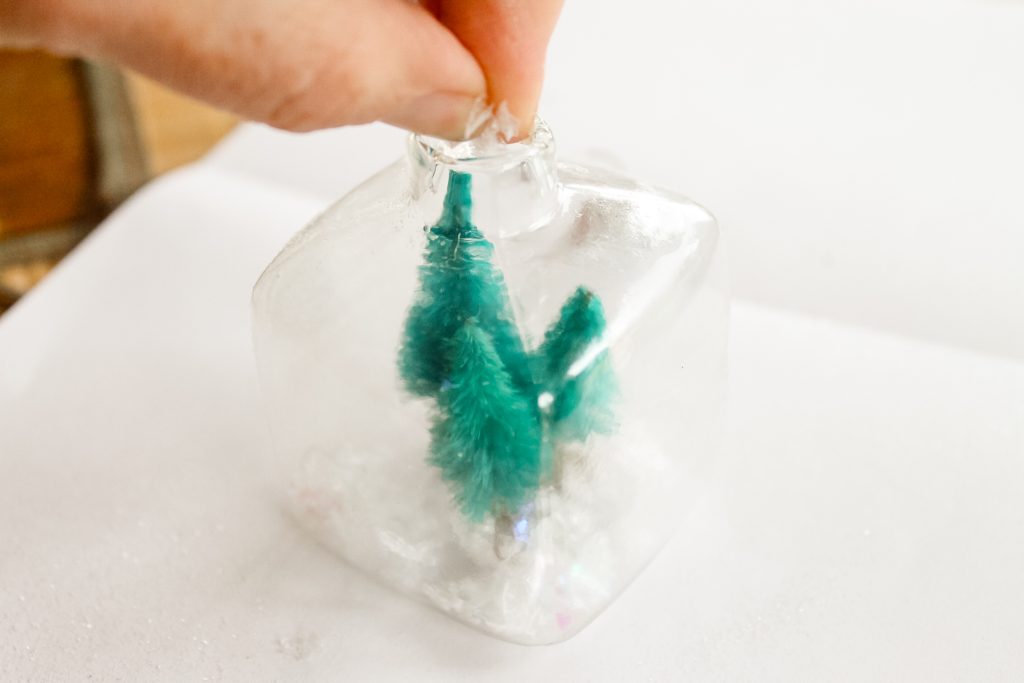 Kids Craft: Mini Snow Globe Ornaments -- click the picture to get the full instructions for making your own fun Christmas ornaments. adding fake snow to ornaments after placing the sisal trees