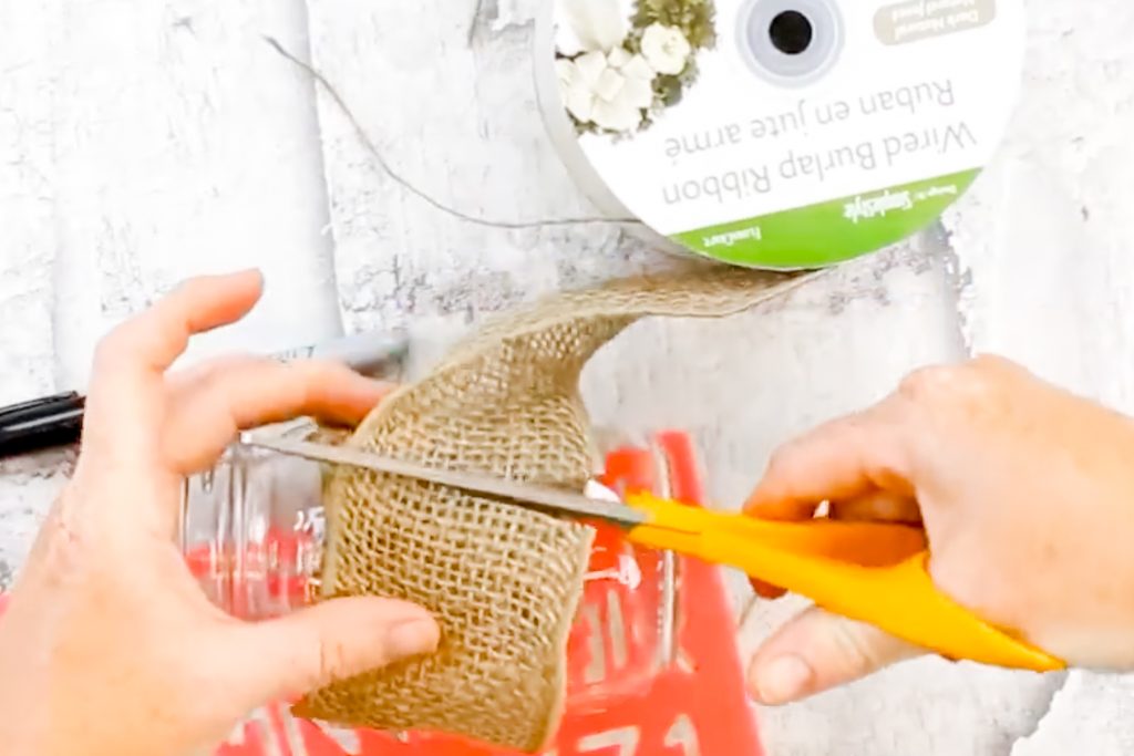 Cutting burlap ribbon to fit around the jar