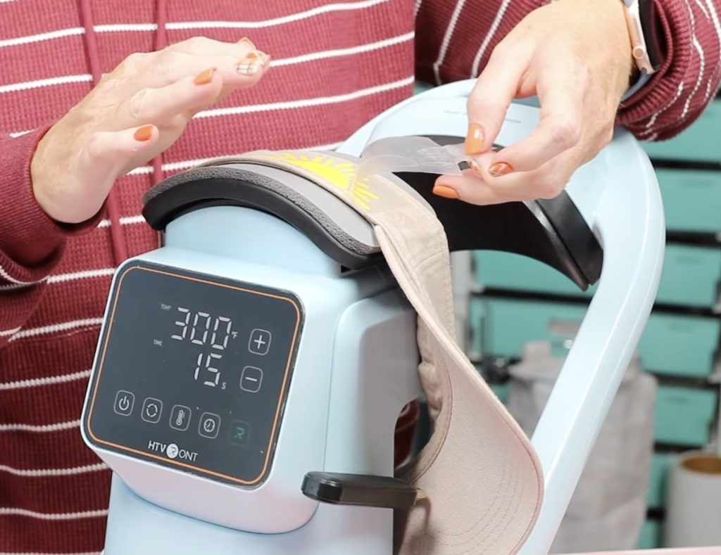 peeling back carrier sheet from htv while hat is in hat press