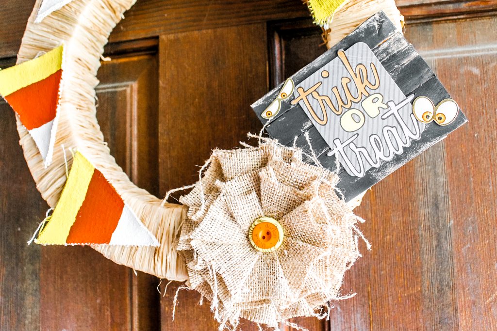 Burlap rosette and trick or treat sign attached to wreath