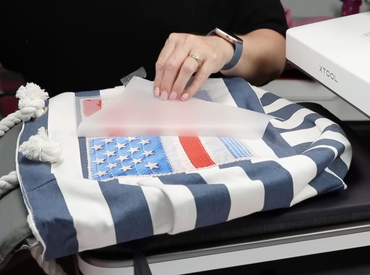 Remove carrier sheet from DTF print on tote bag.
