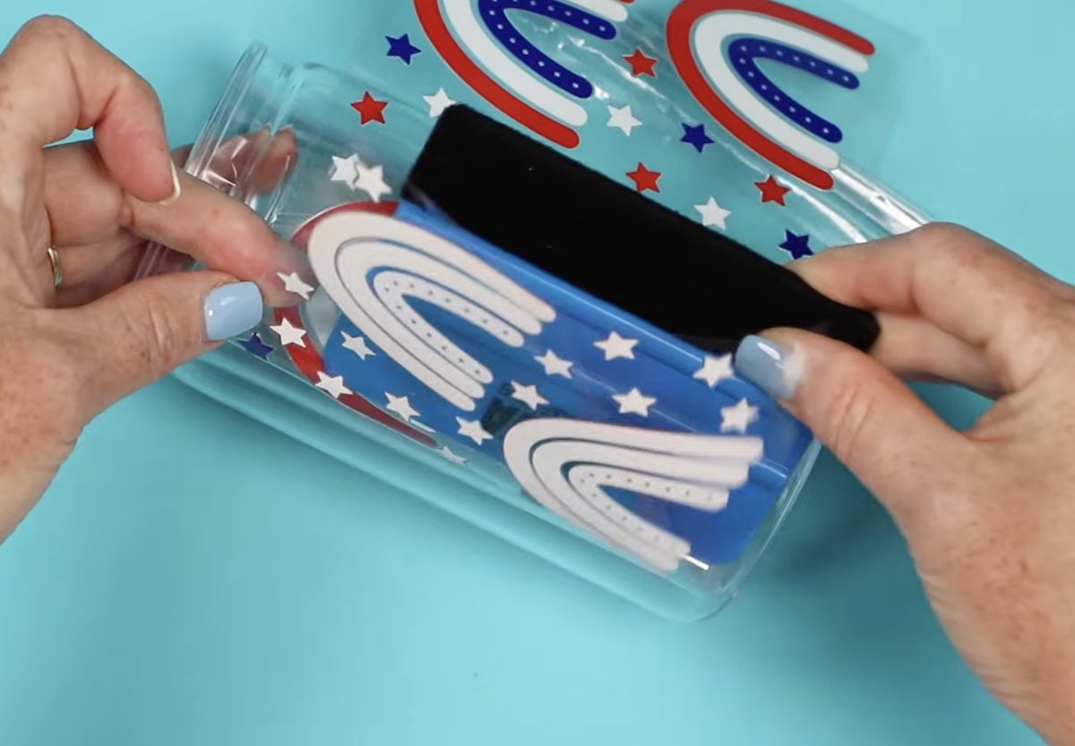 Use a scraper tool to apply the decal to the tumbler.