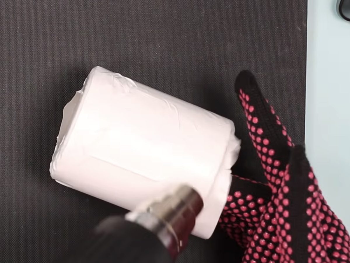 Use a heat gun to shrink the shrink sleeve around the candle jar.