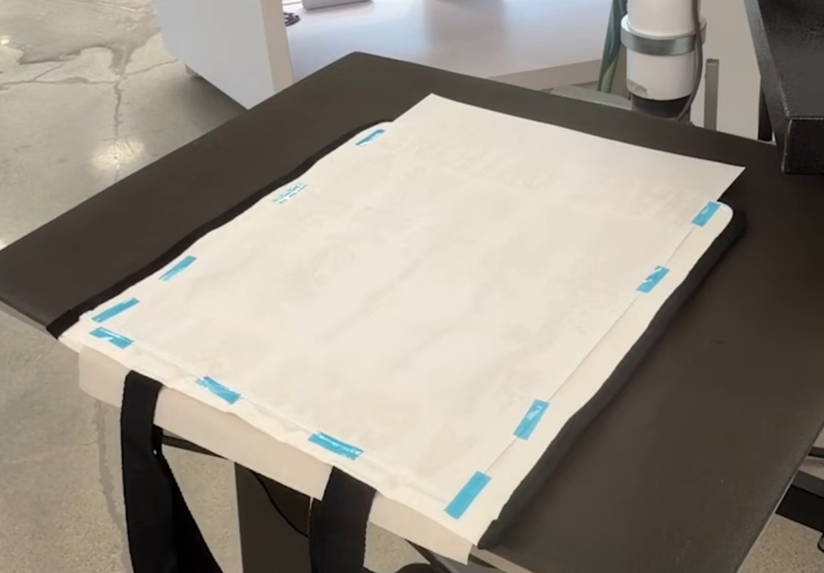 Large sublimation print located on tote bag, secured with heat-resistant tape.